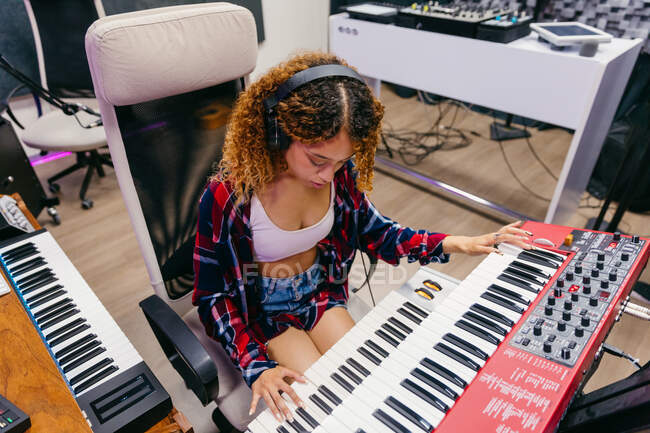 Von oben betrachtet spielt eine afroamerikanische Sängerin im Headset Synthesizer, während sie im Aufnahmestudio einen Song ins Mikrofon spielt — Stockfoto