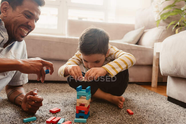 Vista lateral de pai e filho brincando com peças de construção na sala de jantar da casa — Fotografia de Stock