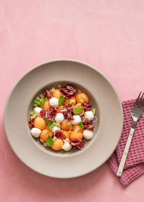 From above exotic melon, mozzarella and prosciutto salad on pink colorful background — Stock Photo
