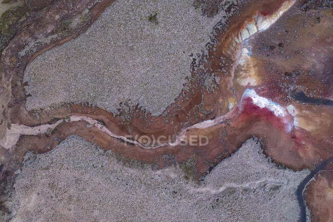 Сверху течет серая вода или река, образуя неровный абстрактный орнамент на пересеченной местности Исландии. — стоковое фото