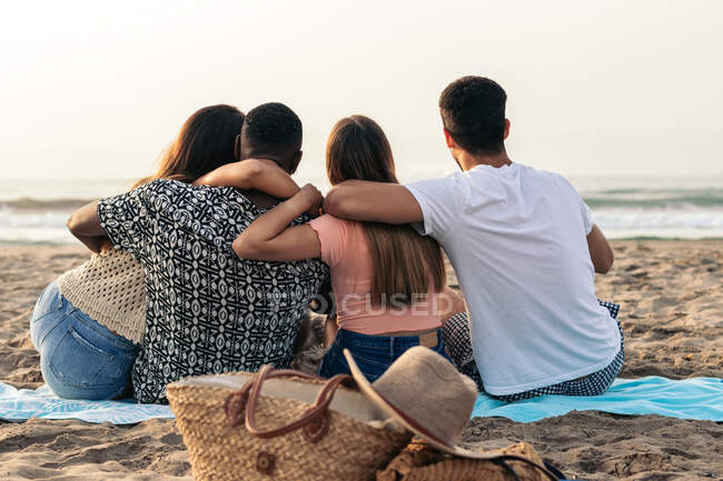 Улітку, сидячи на піщаному пляжі, я милуюся товаришами невідомих різних друзів, які обіймаються. — стокове фото