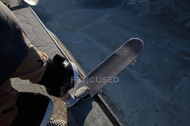 De dessus de la récolte patineur masculin anonyme debout avec planche à roulettes sur la rampe dans le skate park — Photo de stock