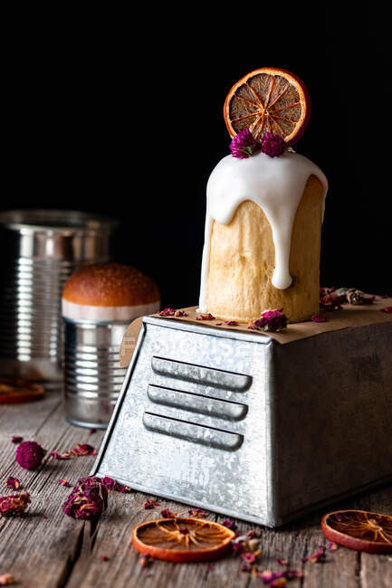 Diversi deliziosi kulichs fatti in casa versati con glassa dolce e decorati con pezzi di arancia secca e fiori sul tavolo di legno — Foto stock