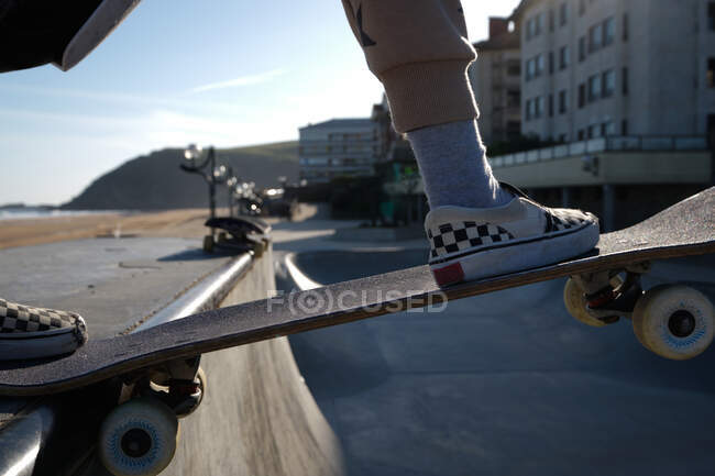 Dall'alto del raccolto anonimo pattinatore maschile in piedi con skateboard su rampa in skate park — Foto stock