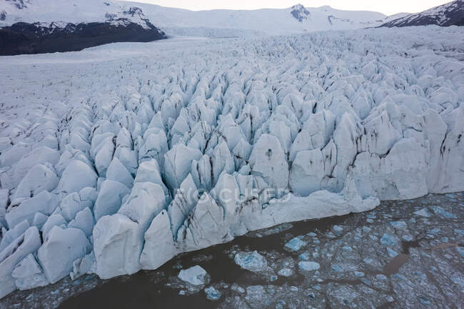 Dall'alto drone vista di banchi di ghiaccio galleggianti su acqua fredda vicino ghiacciaio grezzo in inverno in Islanda — Foto stock