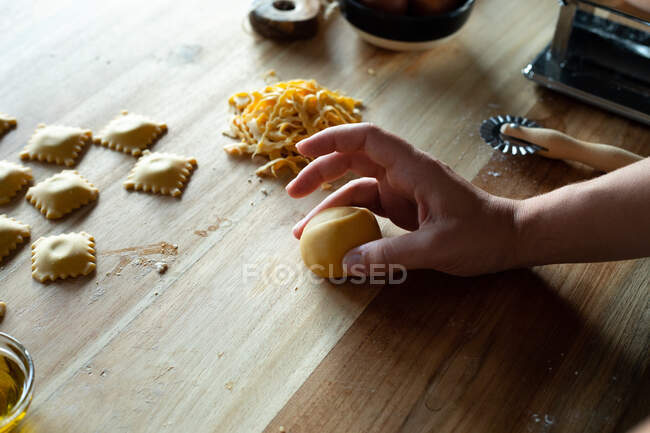 Неузнаваемый человек готовит дома равиоли и макароны. Она формирует тесто. — стоковое фото