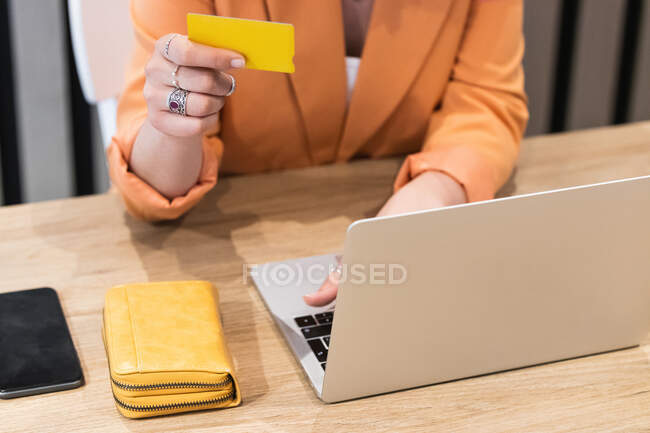 Femme gaie utilisant une carte en plastique et payer pour les achats lors des achats en ligne via un ordinateur portable — Photo de stock