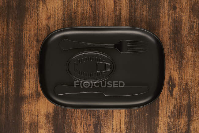 Top view of black fork and knife placed near sealed canned food on rectangular black tray — Stock Photo