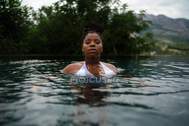 Donna afroamericana in bikini nuotare in acqua limpida in piscina durante le vacanze estive in resort in altopiani — Foto stock