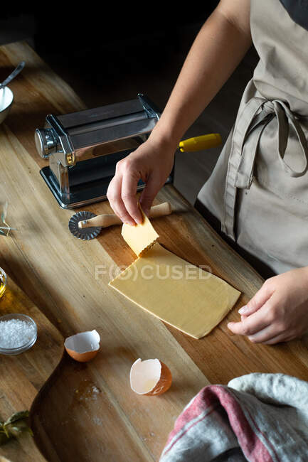 Pessoa irreconhecível preparando raviolis e massas em casa. Ela está a cortar os pratos de massa. — Fotografia de Stock