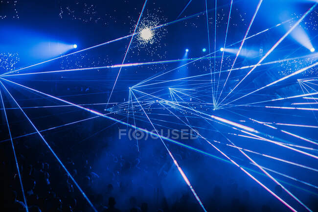 Raios de néon azul brilhante iluminando a moderna sala de concertos escura durante a performance musical ao vivo — Fotografia de Stock