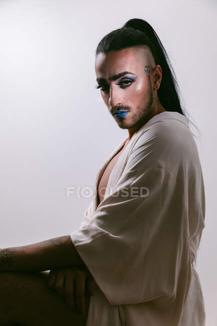 Портрет гламурної трансгендерної бородатої жінки у витонченому змушує дивитися на камеру на нейтральному тлі — стокове фото