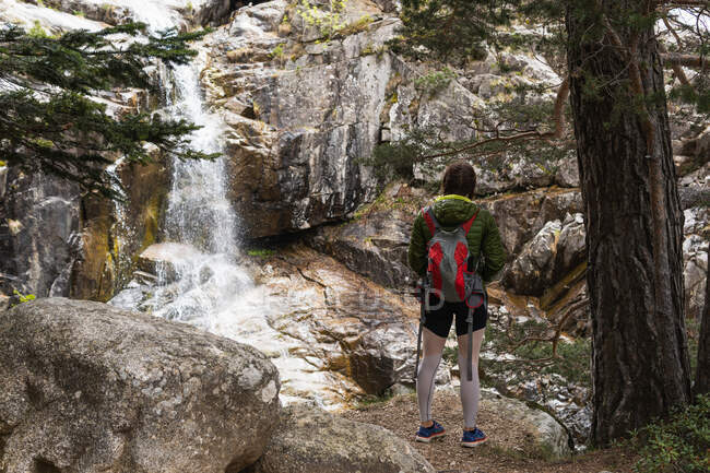 Звернення до анонімної подорожньої жінки, що стоїть на скелі і милується величним водоспадом у горах Піренеїв. — стокове фото