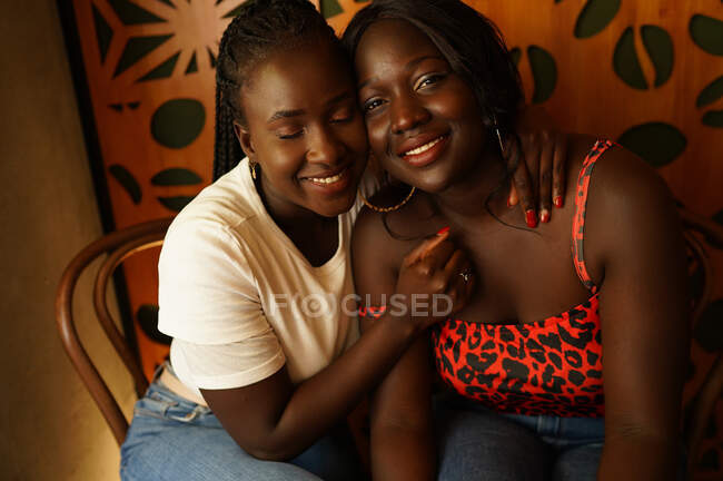 Feliz afro-americano feminino melhores amigos abraçando enquanto refrigeração no café e desfrutar de fim de semana juntos — Fotografia de Stock