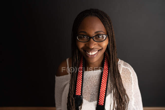 Black female photographer with camera on black background — Stock Photo