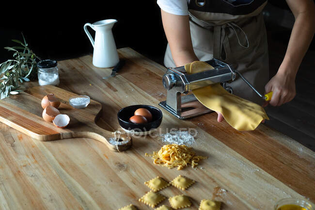 Persona irriconoscibile che prepara ravioli e pasta a casa. Sta usando una macchina per la pasta — Foto stock