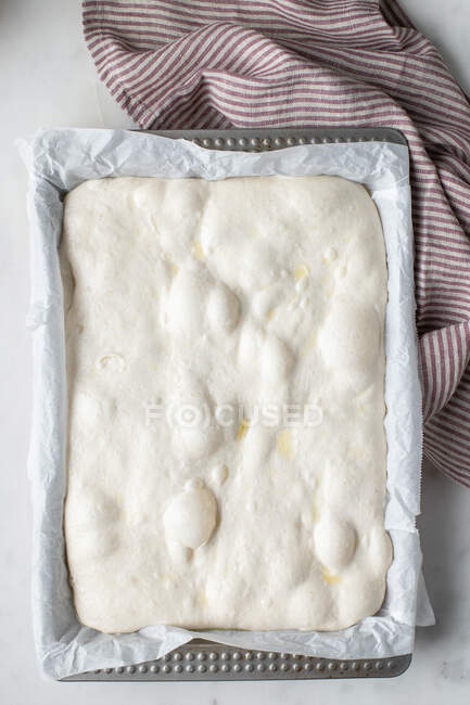 Vista superior da massa caseira colocada no papel manteiga para cozinhar pão tradicional — Fotografia de Stock