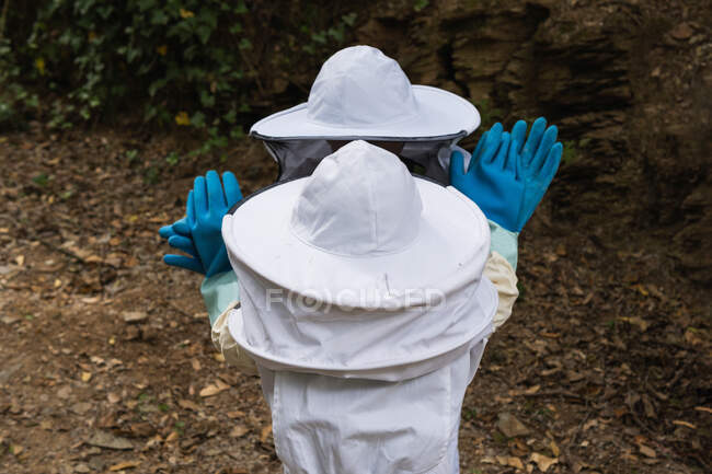 Анонімні діти в білих захисних костюмах і рукавицях, що стоять у саду. — стокове фото