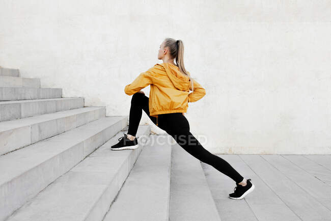 Jeune femme caucasienne athlétique étirant à l'extérieur près des escaliers — Photo de stock