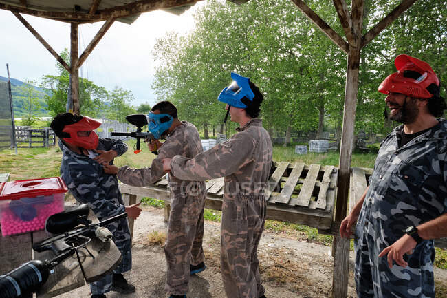 Positive male players in camouflage outfit having fun before playing paintball in countryside — Stock Photo