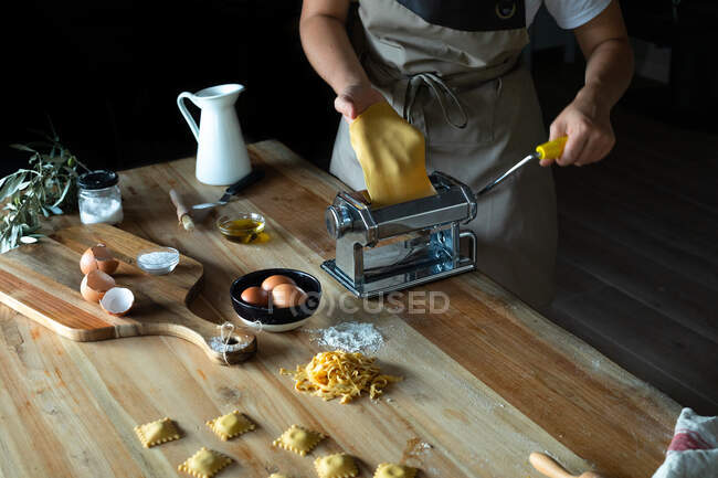 Unbekannter bereitet zu Hause Ravioli und Pasta zu. Sie benutzt eine Nudelmaschine — Stockfoto