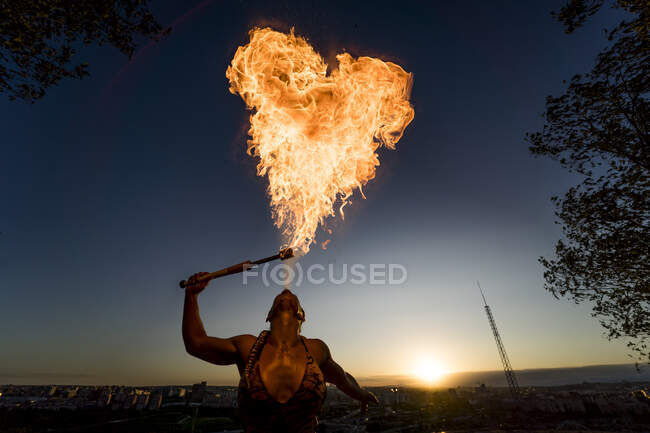 Mangiafuoco donna che esegue sputare fuoco al tramonto — Foto stock