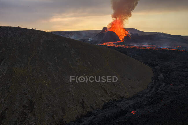 Drone vista do córrego de lava laranja quente que flui através de terreno montanhoso de manhã na Islândia — Fotografia de Stock