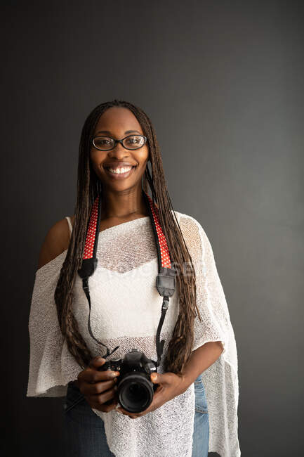 Fotografo nero femminile con fotocamera su sfondo nero — Foto stock