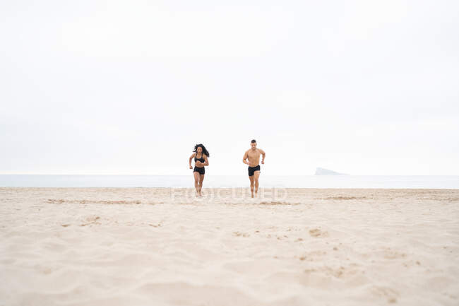 Vielfältige Sportlerinnen und Sportler laufen beim Fitnesstraining im Sommer am Sandstrand — Stockfoto