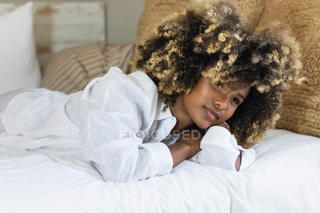 Attraente donna afroamericana sdraiata sdraiata sul letto a guardare la fotocamera — Foto stock