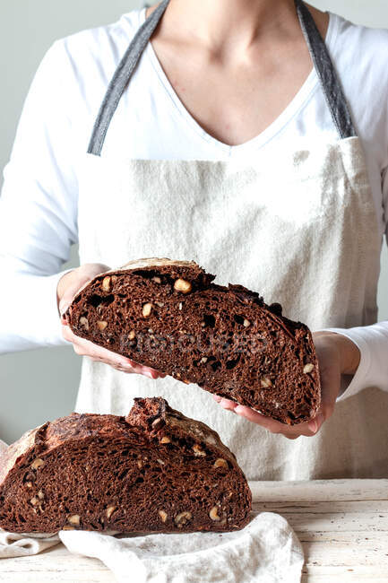 Crop faceless woman hands holding freshly baked sourdough rye bread Crumb pan cutting in half — Stock Photo