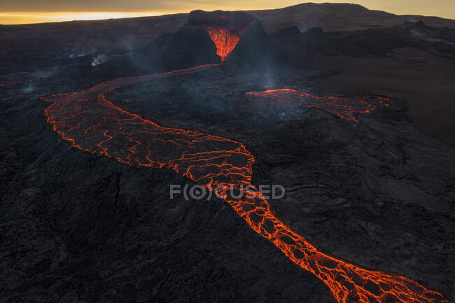 Drone vista del torrente di lava arancione calda che scorre attraverso terreni montuosi al mattino in Islanda — Foto stock