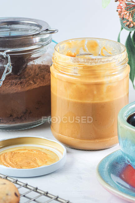 Natureza morta de jarros de vidro com manteiga de amendoim e chocolate em pó — Fotografia de Stock