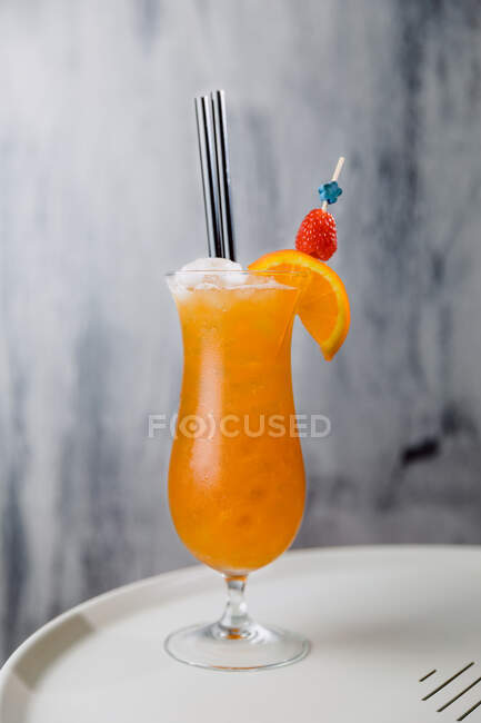 Glass of cold Sex on beach cocktail containing vodka peach liqueur orange juice with straw and ice — Stock Photo