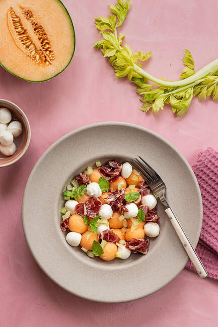 Von oben exotische Melone, Mozzarella und Schinken-Salat auf rosa Hintergrund — Stockfoto
