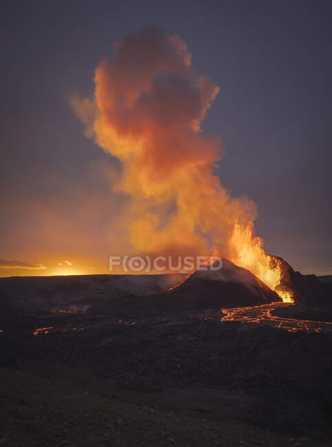 Malerischer Blick auf aktiven Vulkan mit heißer Lava vor wolkenverhangenem Himmel bei Sonnenuntergang in Island — Stockfoto