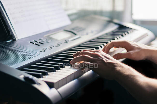 Hombre anónimo tocando un piano en casa - foto de stock