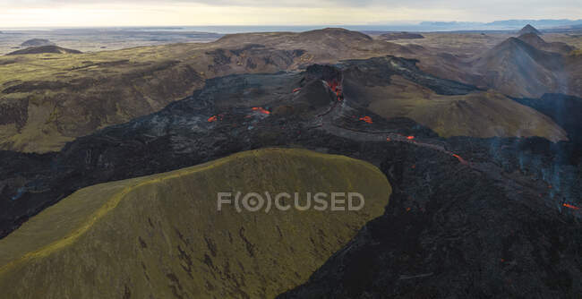 Вид згори на діючий вулкан з гарячою лавою, розташований у нерівній гірській місцевості в Ісландії. — стокове фото