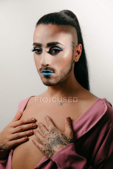 Retrato de mulher barbuda transgênero glamourosa em sofisticado fazer olhando para a câmera contra fundo neutro — Fotografia de Stock