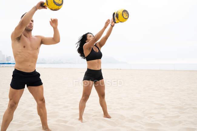 Multiracial-Fit-Sportler und Sportlerin beim Kettlebell-Schwingen während des Trainings am Meer im Sommer — Stockfoto