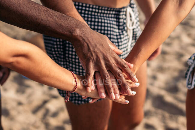 Grupo de amigos irreconhecíveis colheita com as mãos juntas em pé na praia no verão — Fotografia de Stock