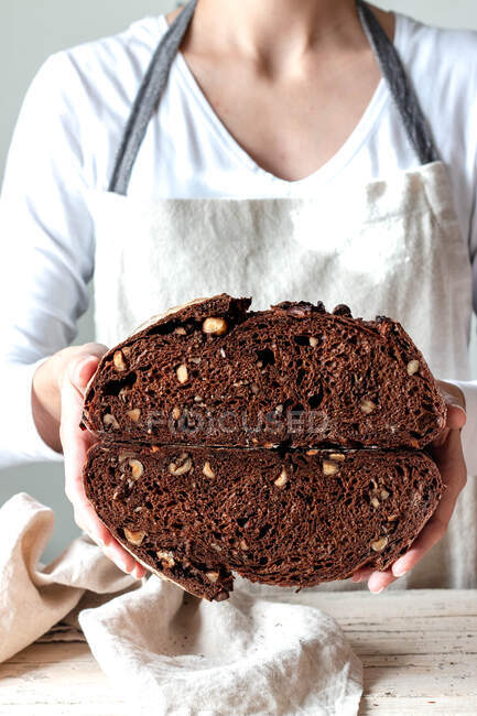 Обрезать лицо женщины руки держа свежеиспеченный ржаной хлеб ржаной хлеб крошка сковороды разрезая пополам — стоковое фото