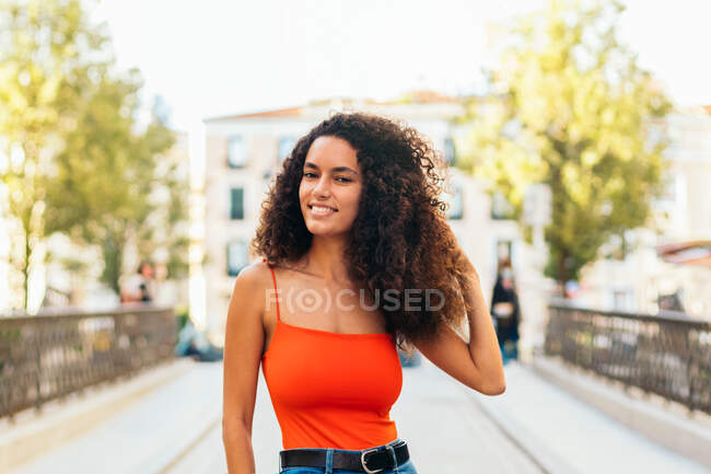 Стильная женщина с вьющимися волосами, стоящая на улице — стоковое фото