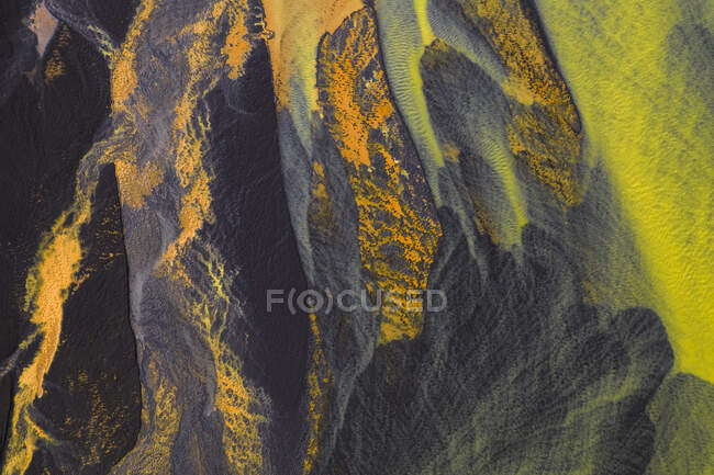 Von oben Luftaufnahme eines Flusses mit orangefarbenem Wasser, das durch die raue Landschaft Islands fließt — Stockfoto