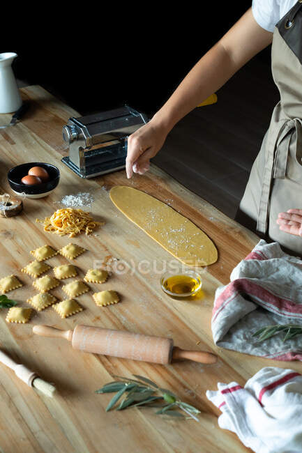 Unrecognizable person preparing raviolis and pasta at home. She is pouring flour into the dough — Stock Photo