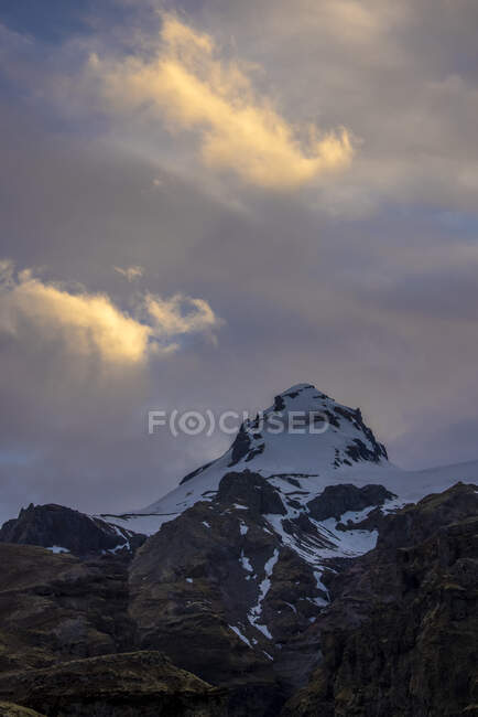 Baixo ângulo do pico da montanha coberto de neve e localizado contra o céu nublado de manhã na Islândia — Fotografia de Stock