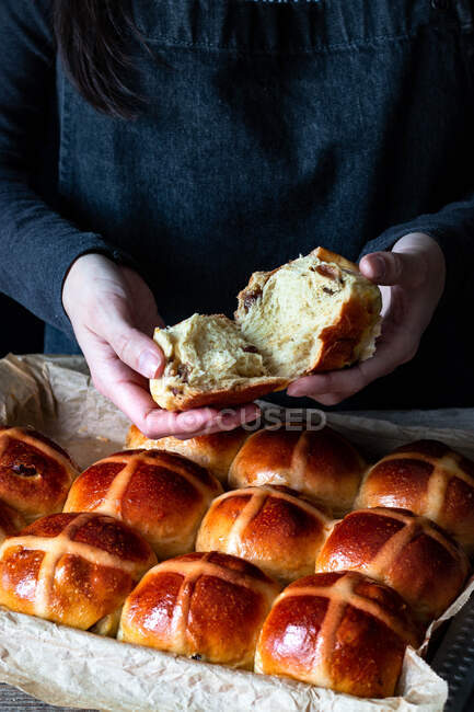 Femmina baker apertura soffio appena sfornato panini caldi croce sulla teglia — Foto stock