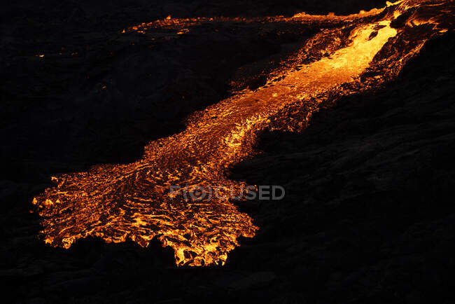 Vue par drone d'un ruisseau de lave orange chaude traversant un terrain montagneux le matin en Islande — Photo de stock