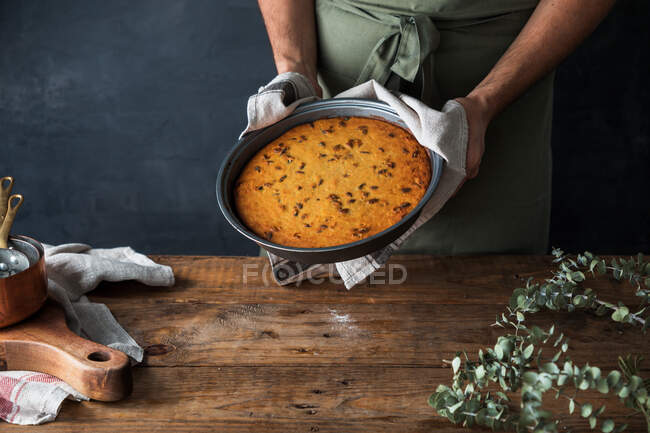 Cropped anônimo cozinheiro masculino segurando prato com deliciosa torta de abóbora na mesa de madeira — Fotografia de Stock