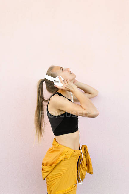 Mujer caucásica joven con auriculares y ropa deportiva y escuchar música - foto de stock